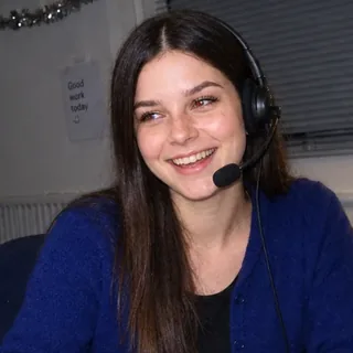 Bow, ARROW's own AI receptionist, smiling on a headset at her desk.